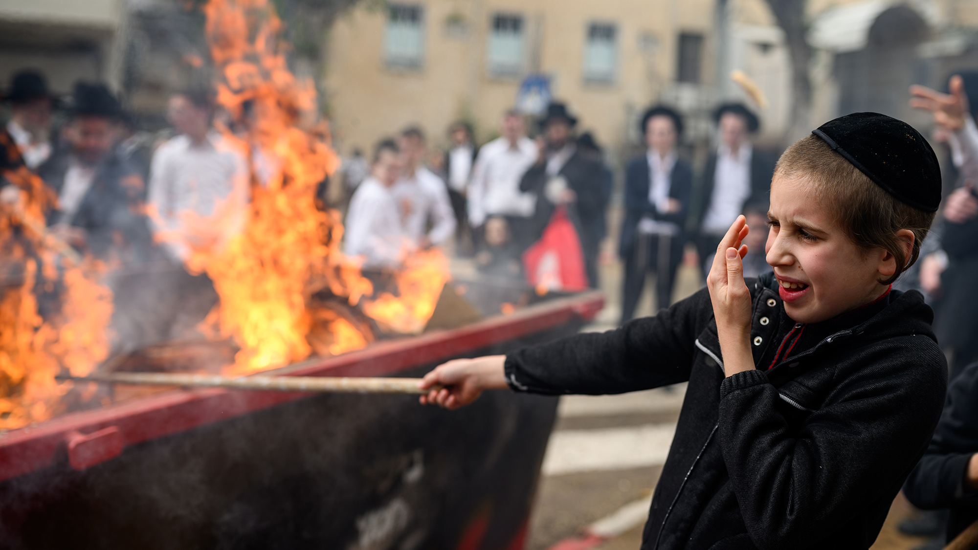 A boy from the Ultra-Orthodox community hides his face from the flames while participating in the burning of chametz (leavened food) that precedes Passover in Bnei Brak, Israel