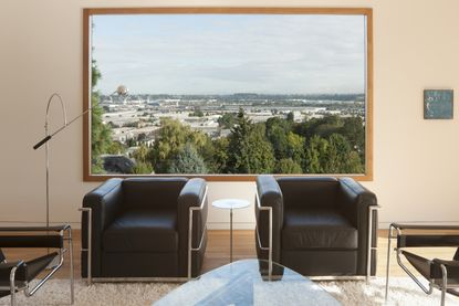 A window onto a landscape view with two black armchairs in front