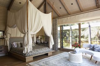 a bedroom with a canopy bed and high wood beamed ceilings