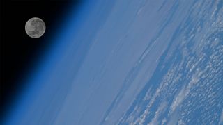 a full moon is seen over the horizon of Earth as viewed from orbit