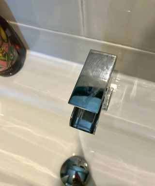 Grey tiled bathroom with silver faucet with water marks