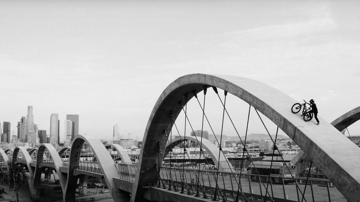 Dylan Stark pushes his mountain bike up a bridge