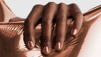 A hand holding a pink balloon wearing JW Anderson x Pleasing pink nail polish