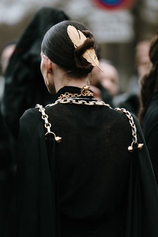 gold feather in a woman's dark hair