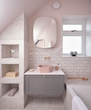 Pink and marble bathroom with marble wall and floor tiles, bath, sink area and custom built shelving with recessed shelves, unique pink hexagon sink