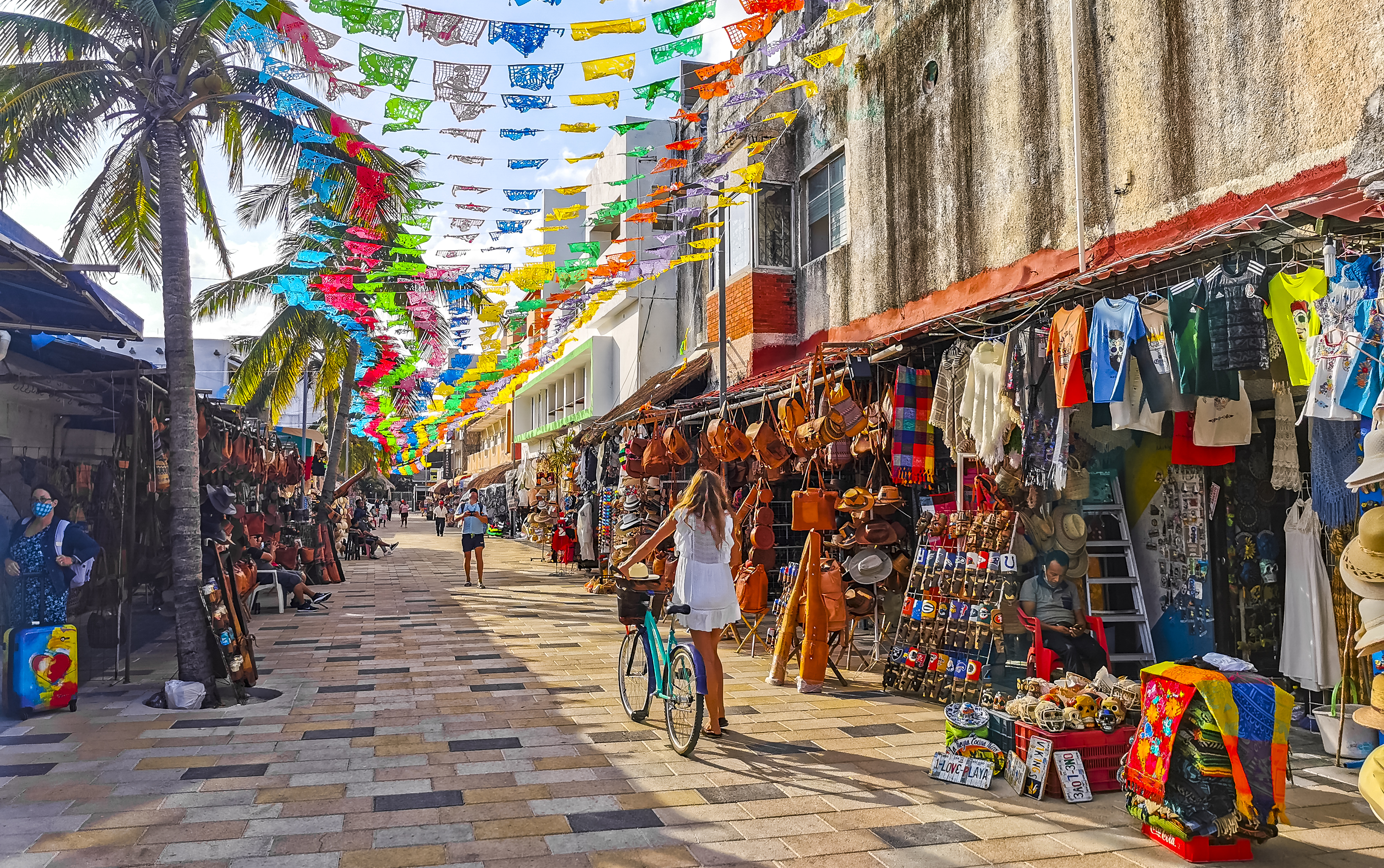 Woman walking her bike on a vibrant street in Mexico
