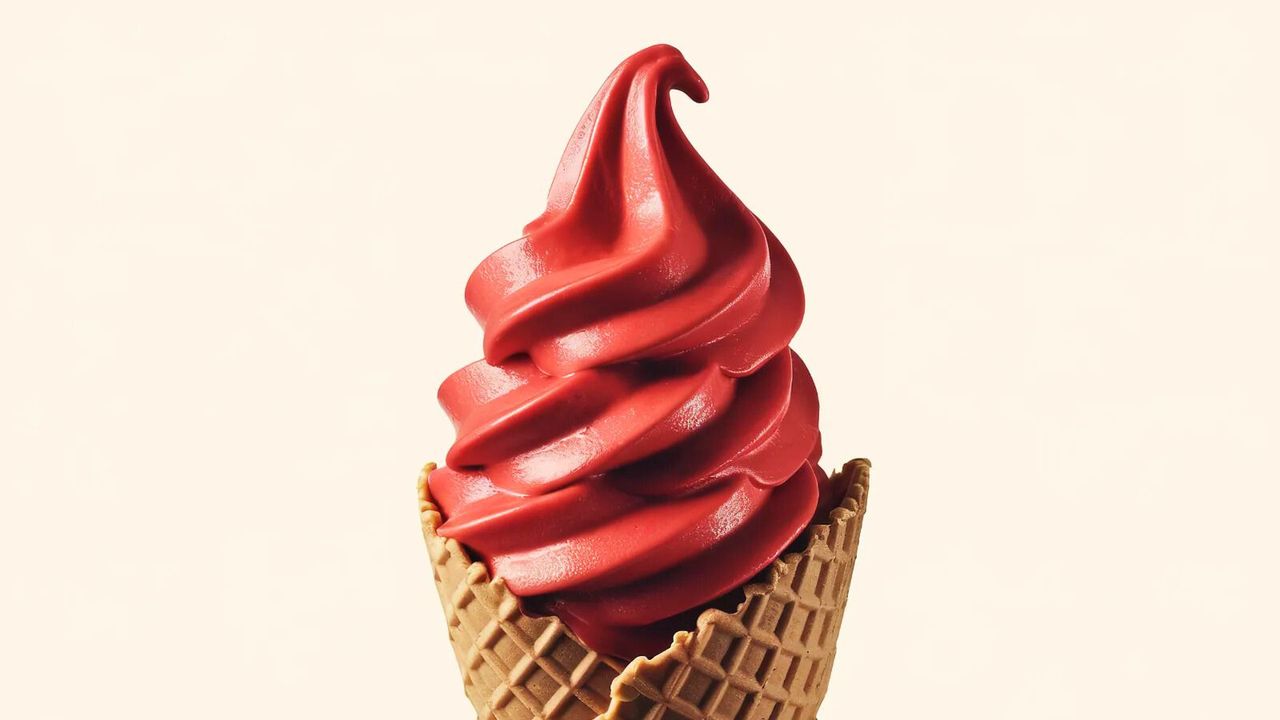 A swirl of soft-serve raspberry ice cream in a cone