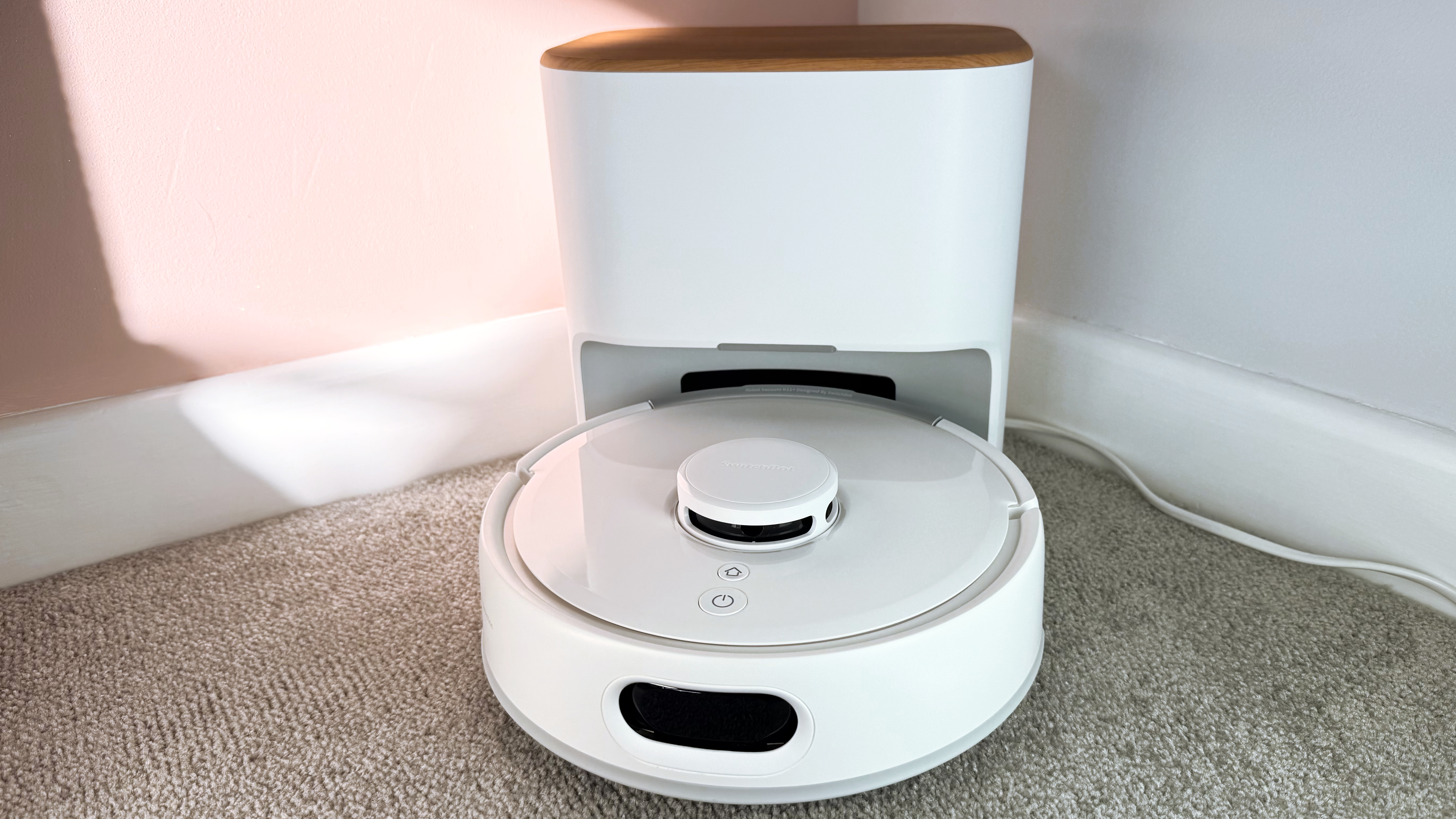 The SwitchBot K11 plus is pictured in front of its dock.