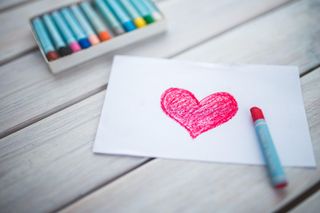 A piece of paper with a heart drawn on it and crayon