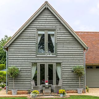 Grey wooden panelled house with bistro set