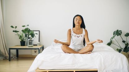 A woman meditating on her bed using the Calm app