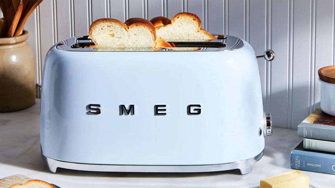 Pale blue Smeg toaster on a countertop with white bread popped up