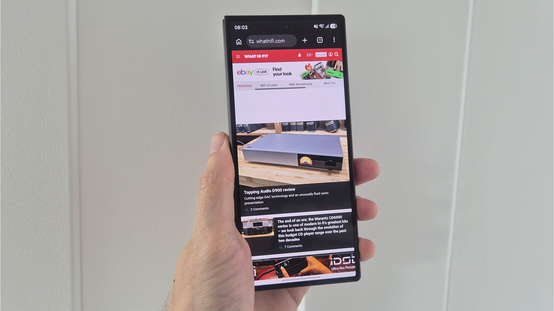 Samsung Z Fold 8 Ultra smartphone held in hand, on screen is What H-Fi? website