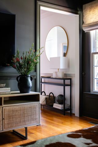 Small entryway painted black with wood floor and console
