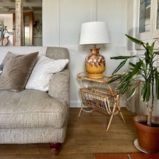 vintage lamp on a rattan side table next to a grey sofa