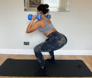 Jade performing the correct squat technique using a pair of dumbbells