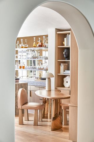 The home bar in a neutral Los Angeles home, with glass bar shelves and mirror backsplash