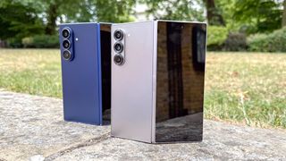 The Samsung Galaxy Z Fold 7 (blue, L) and Galaxy Z Fold 6 stood next to each other, partly folded