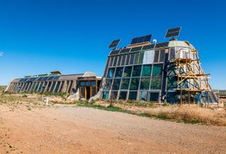 Earthship community in Taos showing colourful off grid homes nestled into the desert earth