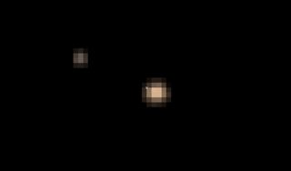 Pluto and its largest moon Charon orbit their mutual center of gravity (marked with 'x') in this still from the first color animation of Pluto from NASA's New Horizons spacecraft captured between May 29 and June 3, 2015. 