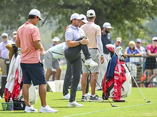 Rory McIlroy stretches before his round on the practice range