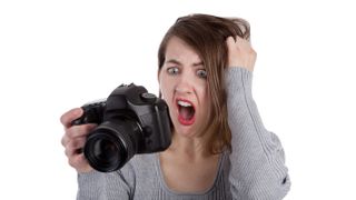A frustrated photographer pulling her hair out as she reads the display screen on the back of her digital SLR camera