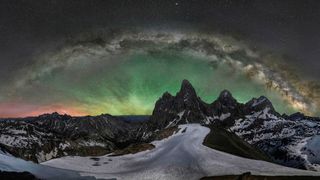 A panorama of the Grand Teton under a halo of green light.