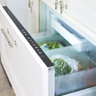 An open freezer drawer containing frozen green vegetables.