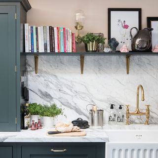 kitchen with white marble on wall and rectangle wash basin with faucet and book shelves with potted plants