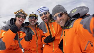 L-R: Cory Michael Smith, Steve Carell, Ramy Youssef and Jason Schwartzman in orange jumpsuits pose for a selfie together in a scene from HBO Max's "Mountainhead"