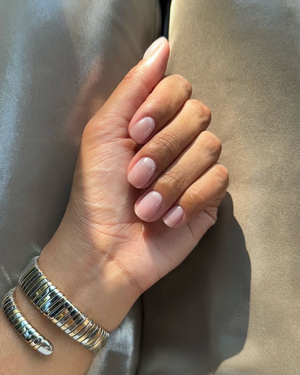 @iramshelton wears a neutral manicure with a gold bracelet