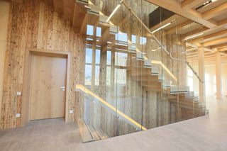 Inside a building at the top of a first floor stairwell. The building's interior is made predominantly with wood.