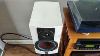 The DALI Rubikore 2 speaker in white from a high angle next to a wooden surface.