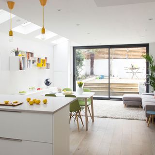 yellow lemons on white counter top next to dining table with green chairs with a view of outside patio