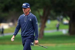 Jake Knapp walks off the putting green holding a putter