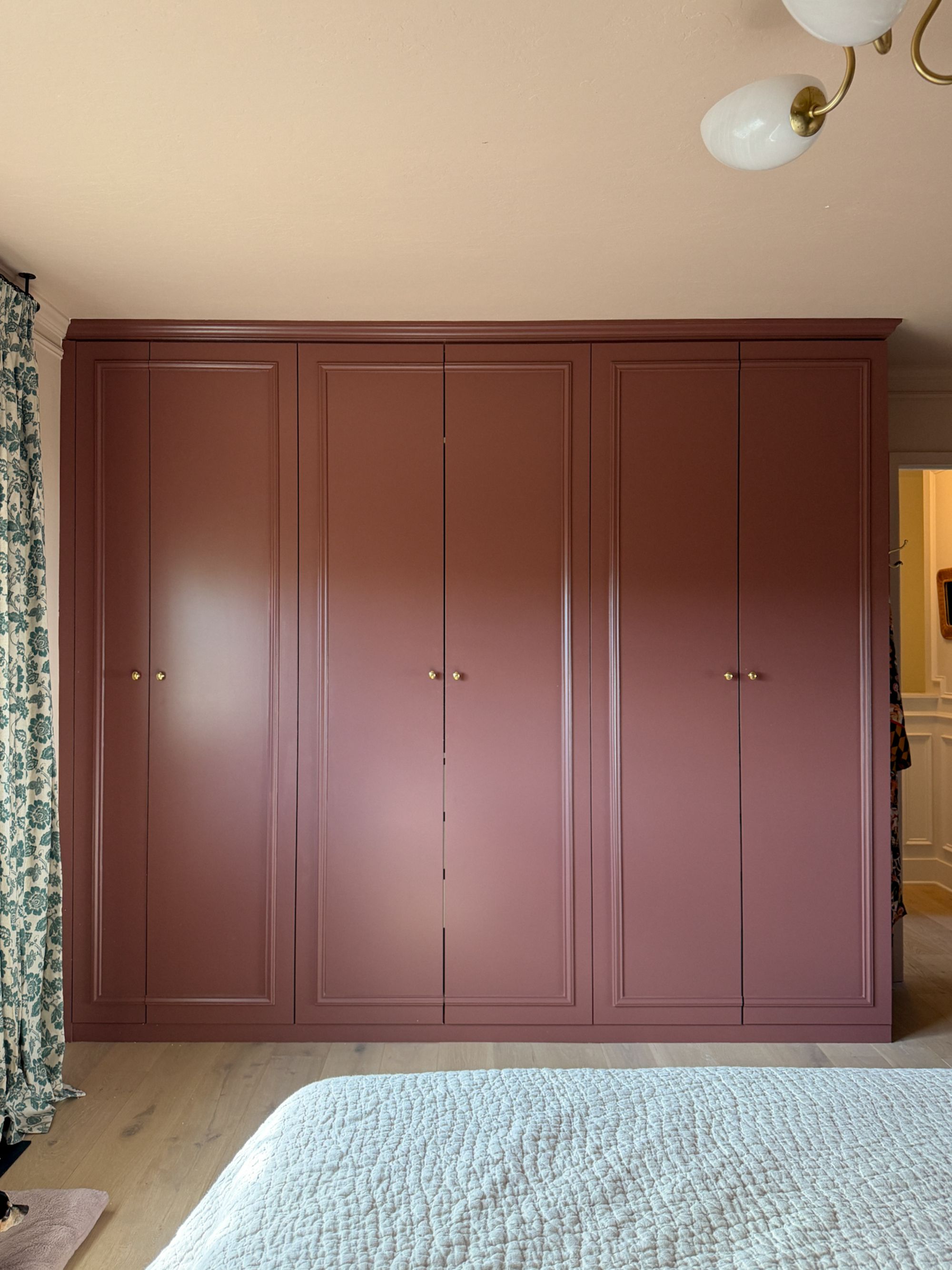 Image of a wine/berry red built-in wardrobe in a light pink bedroom. 