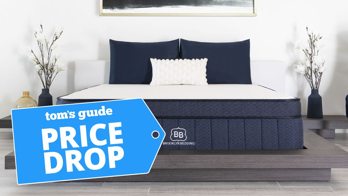 Brooklyn Bedding Aurora Hybrid Mattress on a grey low profile platform bed in a chic bedroom, with a Tom&#039;s Guide Price Drop logo overlaid on the lower left