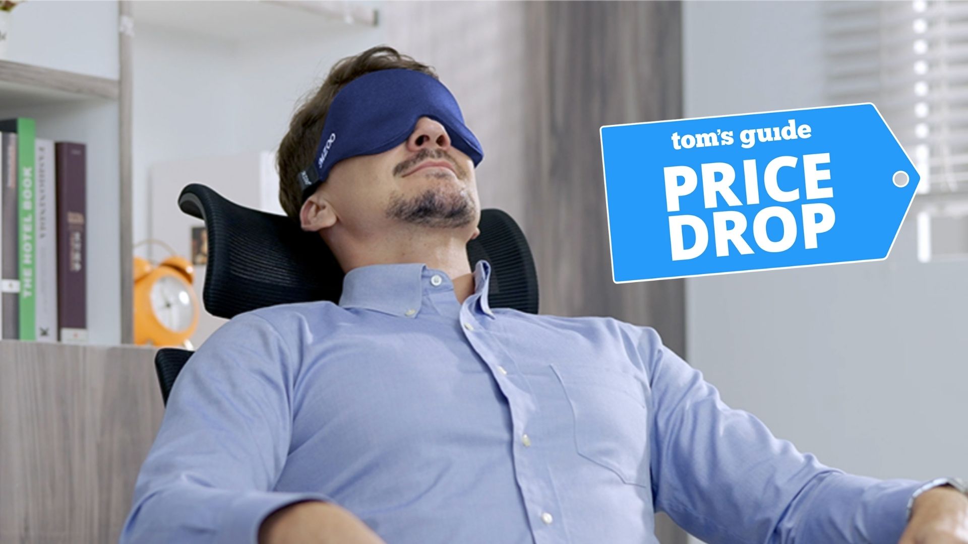 A man wearing blue shirt and blue sleep mask sleeping on office chair