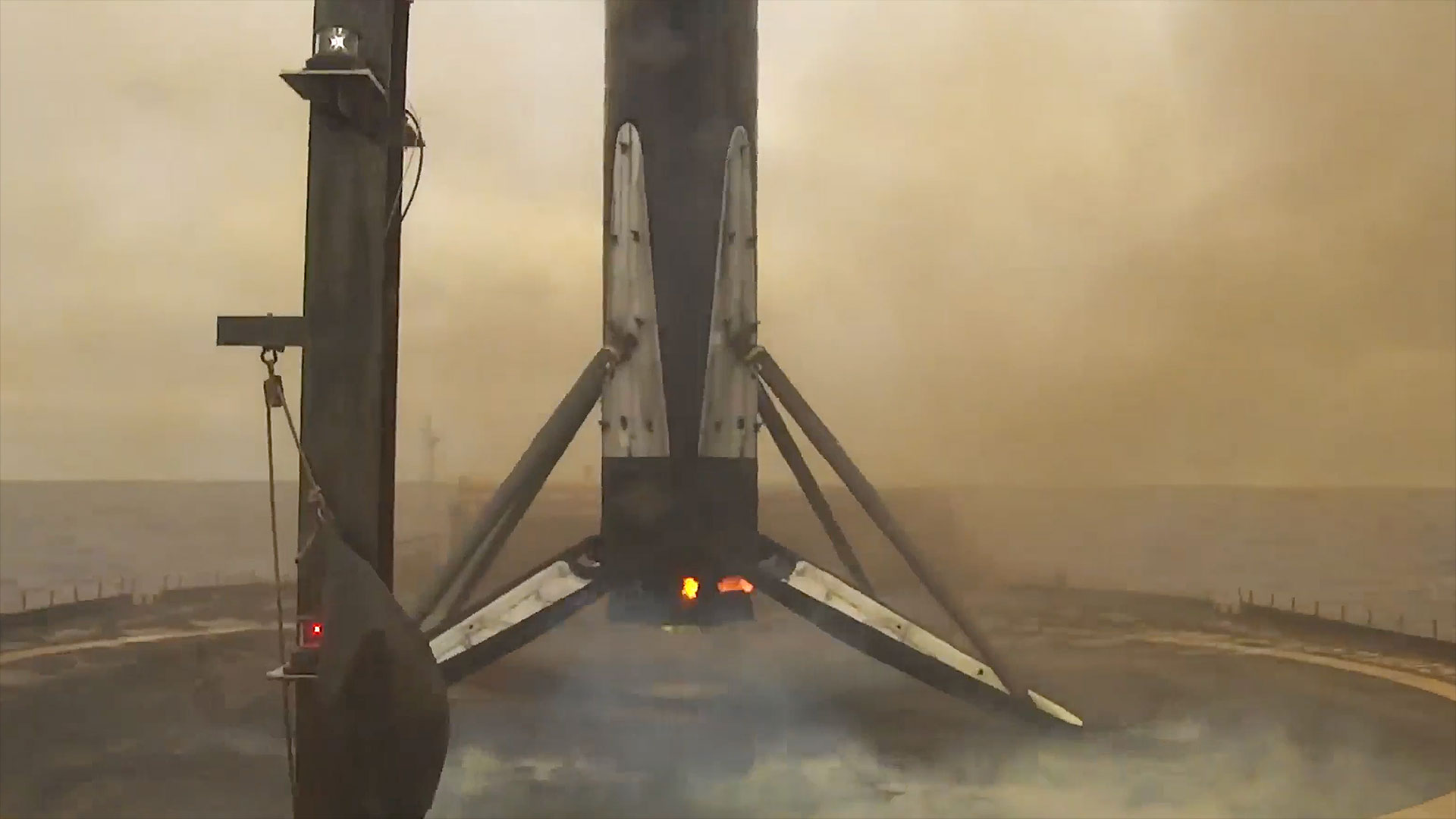 the first stage of a rocket stands on its four legs atop a sea-based drone ship after landing from space