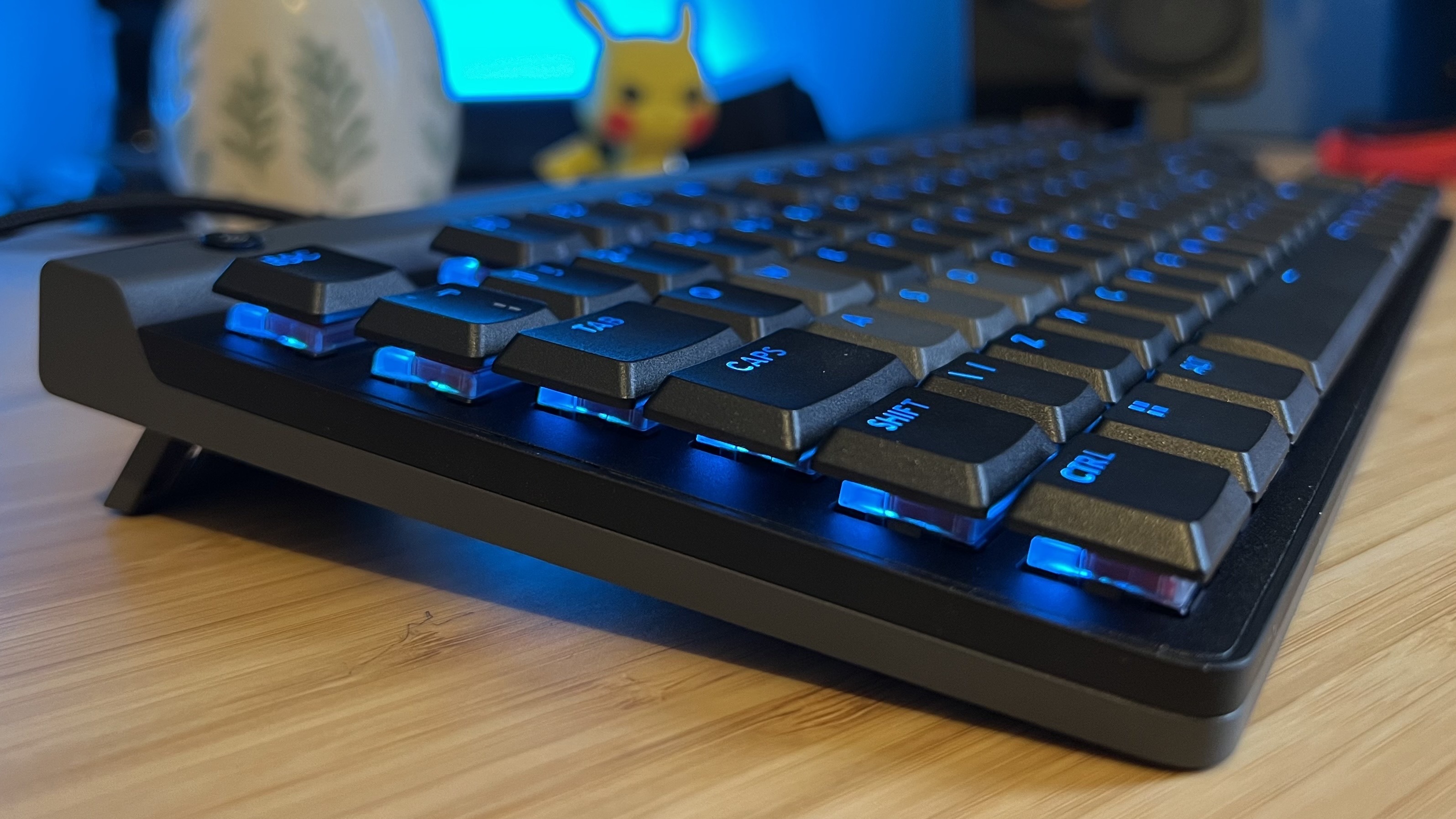 Side view of Logitech G515 Rapid TKL gaming keyboard sitting on a wooden desk