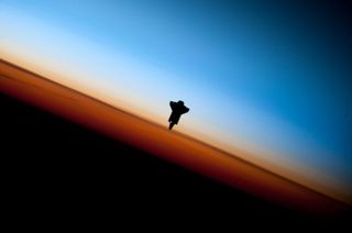In a very unique setting over Earth's colorful horizon, the silhouette of the space shuttle Endeavour is featured in this image photographed by an Expedition 22 crewmember prior to STS-130 rendezvous and docking operations with the International Space Station. Docking occurred at 12:06 p.m. (EST) on Feb. 10, 2010.