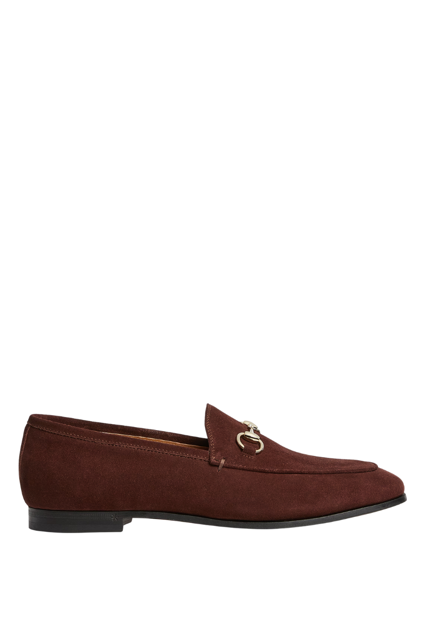 A pair of brown suede Gucci loafers with a horsebit detail. 