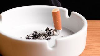 Cigarette snuffed out in a white ash tray