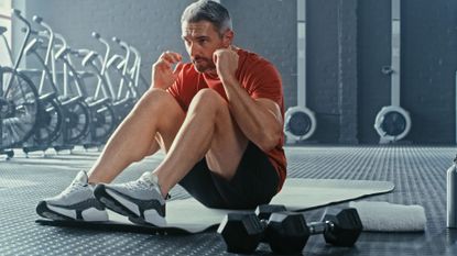 A man completing a core workout with dumbbells in a gym