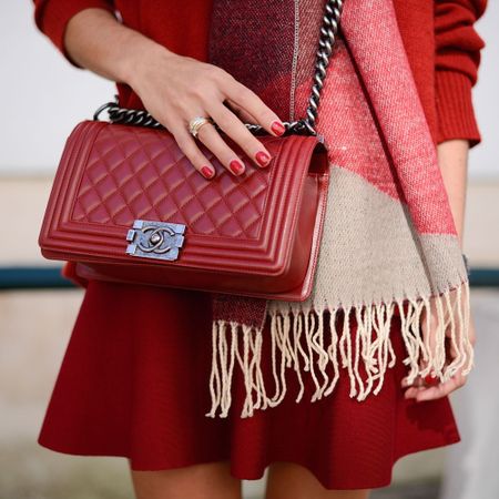 women with shiny red nails and thick ring holds a bag