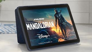 An Amazon Fire HD 10 tablet sits propped up on a kitchen counter. The Mandalorian is showing on the screen. 