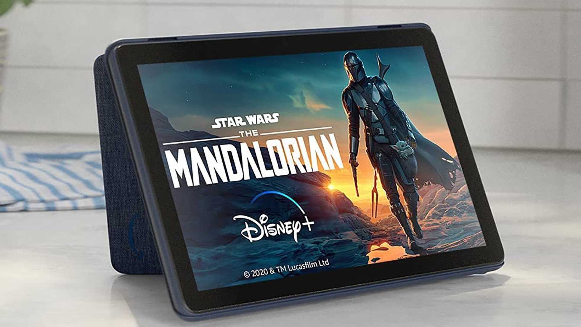 An Amazon Fire HD 10 tablet sits on a kitchen counter.  The Mandalorian appears on screen.