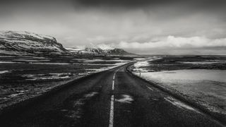 black & white image of a road leading through a barren mountainous landscape