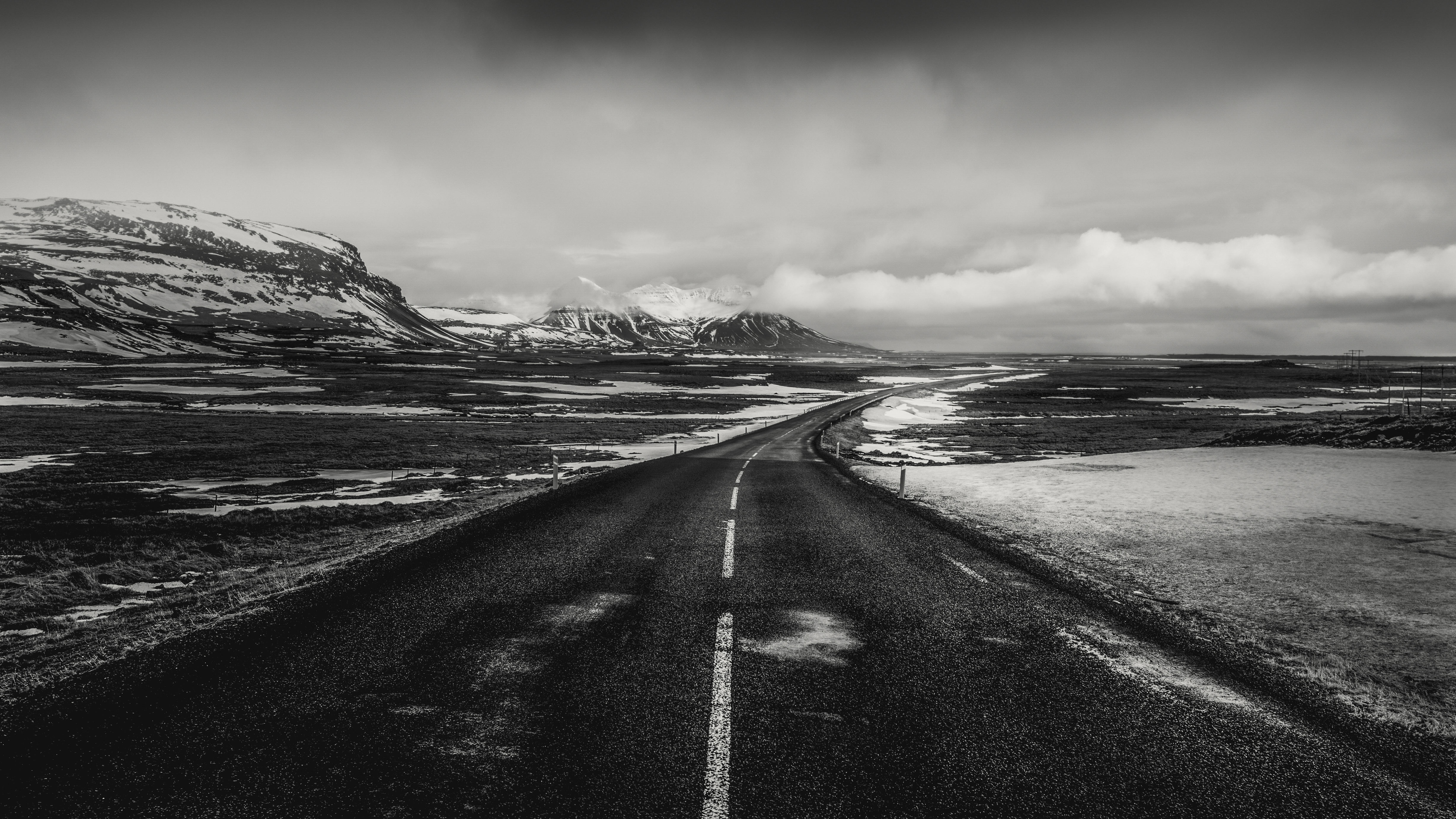 black &amp; white image of a road leading through a barren mountainous landscape