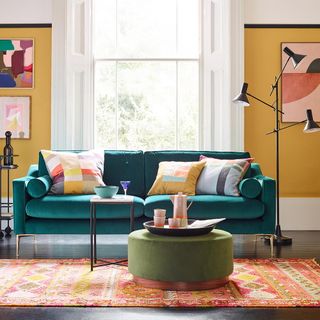 living room with mustard yellow walls and green velvet sofa